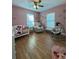Cozy pink Bedroom with a crib, rocker, and baby swing, filled with natural light from two windows at 3623 N 53Rd St, Tampa, FL 33619