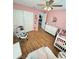 Charming pink Bedroom featuring a crib, changing table, closet, and neutral-toned wooden floors at 3623 N 53Rd St, Tampa, FL 33619