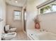 Bright bathroom with a large window, soaking tub, shower, bidet, and tiled floors at 4735 Foxshire Cir, Tampa, FL 33624
