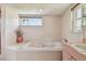 Bathroom featuring tiled walls, soaking tub with jets, and a small window for natural light at 4735 Foxshire Cir, Tampa, FL 33624