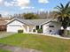 Inviting one-story home with green lawn, minimalist landscaping, palm tree, and a two car garage at 4735 Foxshire Cir, Tampa, FL 33624
