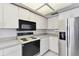 Kitchen featuring white cabinets, stainless steel refrigerator, and black range at 4735 Foxshire Cir, Tampa, FL 33624