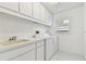 Bright laundry room features white appliances, ample cabinet space, and a practical sink area at 4735 Foxshire Cir, Tampa, FL 33624