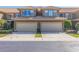Attractive townhome featuring tan stucco and a two-car garage with tiled roof and well-manicured landscaping at 4739 Silverking Way, Palm Harbor, FL 34684