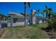 Back exterior view of the home highlighting its stucco siding, fenced yard and manicured landscaping at 8155 Elisabeth Ln, Seminole, FL 33777