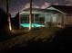Screened-in pool glows invitingly in the landscaped backyard at night at 8941 Southbay Dr, Tampa, FL 33615