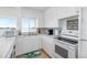 Galley kitchen featuring white appliances and cabinets, with views of the water at 9696 Little Gasparilla Isand, Placida, FL 33946