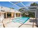 A sparkling swimming pool is surrounded by an enclosed lanai and a lush backyard at 14472 Linden Dr, Spring Hill, FL 34609