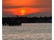 Sunset over the water featuring a dock and silhouettes of distant trees and buildings at 11005 5Th E St, Treasure Island, FL 33706