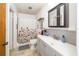 Bright bathroom with a shower, floral shower curtain, and vanity featuring a gray tiled backsplash at 12111 Scott Dr, Dade City, FL 33525