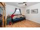 Bedroom with hardwood floors, futon, window with grey curtains, side table and decorated with framed artwork at 12111 Scott Dr, Dade City, FL 33525