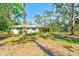 The back of the home is white with a screened in porch and gorgeous, mature trees at 13450 Wilcox Rd, Largo, FL 33774