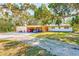 Inviting home exterior featuring a convenient carport, lush trees, and a spacious gravel driveway at 13450 Wilcox Rd, Largo, FL 33774