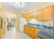 View of kitchen with wood cabinets and breakfast bar, leading into the dining area at 13450 Wilcox Rd, Largo, FL 33774