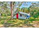 Backyard building with a red door and covered with a tarp, set amongst lush greenery at 13450 Wilcox Rd, Largo, FL 33774