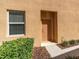 Exterior front entrance featuring a neutral-colored door, window with blinds, and manicured landscaping at 13946 Snapper Fin Ln, Tampa, FL 33637