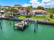 Aerial view of the waterfront property with dock, boat lift and pool surrounded by lush landscaping at 205 Harrison Ave, Belleair Beach, FL 33786
