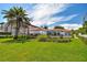 Expansive backyard featuring lush lawn, mature palm trees, deck and inviting outdoor living space with tile roof at 205 Harrison Ave, Belleair Beach, FL 33786