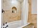 Bathtub with shower, travertine tile surround and niche for toiletries at 205 Harrison Ave, Belleair Beach, FL 33786