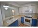 Galley kitchen featuring white cabinets, blue lowers, and stainless steel appliances at 3399 Mermoor Dr # 110, Palm Harbor, FL 34685