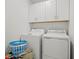 Laundry room with a washer and dryer and overhead white storage cabinets at 36419 Garden Wall Way, Zephyrhills, FL 33541