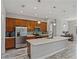 Well-lit kitchen boasts wood cabinetry, stainless steel appliances, a large island, and stylish pendant lighting at 4043 Salida Del Sol Dr, Sun City Center, FL 33573
