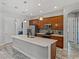 This kitchen includes a large island, wood cabinets, stainless appliances, tile backsplash, and stylish pendant lights at 4043 Salida Del Sol Dr, Sun City Center, FL 33573