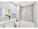Bright bathroom with vanity, bathtub, and shower featuring stylish marble-look tile and decorative floral wall art at 5050 Emerson S Ave, St Petersburg, FL 33707