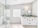 Modern bathroom featuring double vanity, granite countertop, dual round mirrors, glass block window, and walk-in shower with marble tile at 5050 Emerson S Ave, St Petersburg, FL 33707