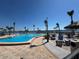 Large community pool with an island, tiki hut, lounge chairs, and palm trees overlooking the bay at 5108 Brittany S Dr # 903, St Petersburg, FL 33715