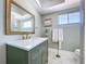 Bathroom boasts granite countertop vanity, framed mirror, decorative art, and marble-look tile at 7960 2Nd N St, St Petersburg, FL 33702