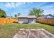 View of backyard featuring a shed with green grass, wooden fence, and sunny skies at 8308 N Mulberry St, Tampa, FL 33604
