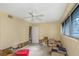 Bedroom with ceiling fan and a window, featuring boxes and signs of damage needing repair at 100 Buena Vista S Dr, Dunedin, FL 34698