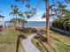 Scenic park view with a walking path leading to tranquil waters, framed by mature trees and lush landscape at 100 Buena Vista S Dr, Dunedin, FL 34698