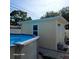 View of pool with beige outbuilding, white trim, pavers, next to white fence and lush trees at 1149 6Th Ne Ave, Largo, FL 33770