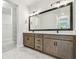 A modern bathroom featuring a double vanity, marble tile flooring, and a large mirror at 11842 Richmond Trl, Parrish, FL 34219