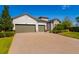 Inviting home with a spacious three-car garage and a brick paver driveway, framed by lush greenery at 12031 Medley Ter, Lakewood Ranch, FL 34211
