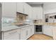 A kitchen area with white cabinets, stainless steel appliances, and a decorative backsplash at 1227 Darlington Oak Ne Cir, St Petersburg, FL 33703