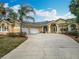 Stunning single-story home featuring a three-car garage and a well-manicured front yard with mature palm trees at 13148 Huntington Woods Ave, Spring Hill, FL 34609