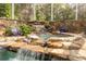 Close-up view of the pool's rock waterfall feature, surrounded by lush landscaping at 1354 Sturbridge Ct, Dunedin, FL 34698