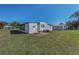 Exterior view of the property featuring an expansive yard with a small patio area, ideal for outdoor enjoyment at 196 Philadelphia Blvd # 10, Palm Harbor, FL 34684