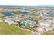 An aerial view shows a community pool with sun loungers, umbrellas, and community buildings nearby at 3231 Hilltop Cir, Bradenton, FL 34211