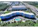 Stunning aerial view of a modern, bright blue condo building with a community pool surrounded by lush trees and landscaping at 3315 58Th S Ave # 314, St Petersburg, FL 33712