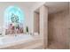 Soaking tub and walk-in shower with decorative arched window and bright natural light at 6014 Mariners Watch Dr, Tampa, FL 33615