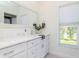 Bright bathroom with marble countertop, white cabinets, and a large framed mirror at 6014 Mariners Watch Dr, Tampa, FL 33615