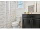 Bathroom featuring decorative shower curtain, dark cabinets, toilet, and vanity with framed mirror at 6251 Camino Dr, Apollo Beach, FL 33572