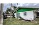 Exterior view of white and green home with tidy lawn and mature trees at 7124 Jasmin Dr, New Port Richey, FL 34652