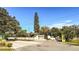 A sunny street view of a property with a gate in front and a very tall tree in the landscape at 7124 Jasmin Dr, New Port Richey, FL 34652