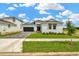 Attractive single-story home with green lawn, two-car garage and long paver driveway with bright blue sky at 10432 Torchwood Sea Way, San Antonio, FL 33576