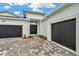 Exterior showcasing a paver driveway leading to a two-car garage and a pair of double front doors at 10432 Torchwood Sea Way, San Antonio, FL 33576